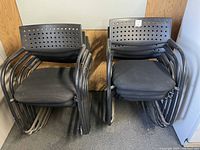 Two stacks of black metal frame stacking chairs with plastic backs and cloth seats, showing 5 chairs in each stack.