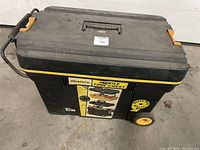 Closed black and yellow Workforce mobile tool chest showing front with label, wheels, and retractable handle.