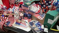 Overview of various 4th of July-themed decorations on a table including flags, plush bears, candles, and partyware.