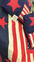 Close-up of the American flag themed throw and pillows showing large red stars on a deep blue background, red and white stripes