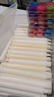 Photo showing white dripless taper candles neatly stacked in a plastic shoe box.