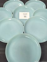 Eight turquoise Fire King plates arranged in two groups with a MaxSold card showing the lot number 55.