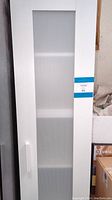 Front view of white IKEA storage cabinet with corrugated plastic panel door, showing door handle and cabinet height.