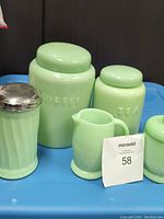 Grouped photo showing all pieces: coffee canister, tea canister, sugar shaker, creamer, and sugar bowl on a blue surface.