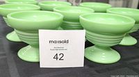 Set of 8 jadeite green footed ice cream cups arranged closely together showing their color and shape with a display card in front.