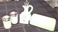 Photo showing all four items: butter dish, cruet with glass stopper, and salt & pepper shakers on a black tablecloth.