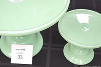 Close-up of two jadeite look cake stands side by side on black cloth