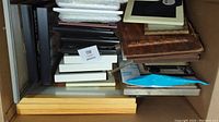Large box filled with assorted picture frames in various colors and sizes packed flat