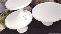 Set of three white cake stands with varying diameters, displayed side-by-side.