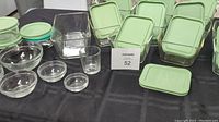 Photo showing twelve 1 7/8 cup glass storage containers with green snap lids, nested glass pinch bowls, and three 1 cup storage containers.