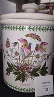 Close-up of the crock's front showing the Helleborus Niger floral design with butterflies and green leaf border.