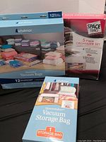 Three new boxes and one opened box of vacuum storage bags and a 5-piece organizer set.
