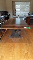 Front view of the wooden dining table showing the extended length and solid construction.