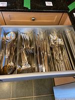Photo showing entire drawer with sections holding multiple types of flatware with floral inlaid handles.