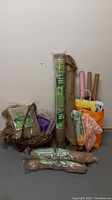Full lot of garden burlap, wicker basket, gift bags, wrapping paper, and packing materials shown against plain wall on floor.