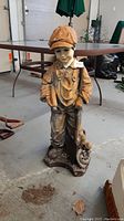 Front view of the garden figurine showing the boy's facial features, cap, and clothing details