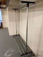 Full view of the metal rolling clothes storage rack showing the full frame and hanging bar.