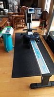 Full Infiniti R100 rowing machine on black protective floor mat in living space