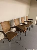 Four iron frame wicker chairs lined up against a wall, showing the seat covers on some chairs.