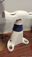 Front angle view of white Back2Life device showing ergonomic backrest and blue spiral base.
