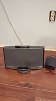 Front view of Bose SoundDock speaker system with remote on top and power adapter on the side.