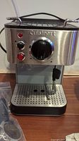 Front view of stainless steel and black Cuisinart espresso machine with control knob and steam wand.