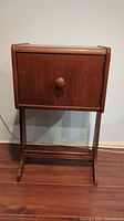 Front view of walnut smokers stand with closed cabinet door, wooden knob, and curved legs.