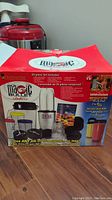 Closed box showing Magic Bullet Deluxe branding and overview of included 25-piece set components.