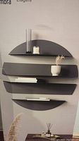 Photo showing all four black semicircular shelves mounted on a wall with small decor items, demonstrating size and shape.