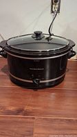 Photo showing black Hamilton Beach oval portable slow cooker with glass lid and temperature control knob