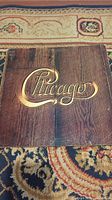 Front cover of Chicago album with gold embossed logo on wood-like background.