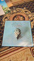 Front cover of Eagles Greatest Hits vinyl record album showing eagle head artwork on blue background.