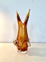 Full view of the amber chalet glass vase showing the pointed double-spout top and clear glass loop decorations on the sides.