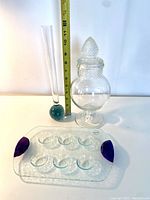 Full view of the antique apothecary jar with stopper lid, glass bubble vase with blue bubble base, and clear textured Dansk egg tray with purple handles
