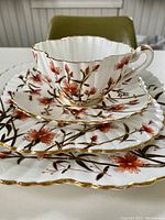 Stacked set showing teacup, saucer, and plates with detailed gold gilding and floral pattern