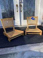 Pair of ash wood folding canoe chairs with cane seat and backs displayed outdoors. One chair shows a tag attached to the cane back.