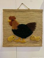 Front view of vintage hand loomed jute wall hanging showing the full hen and chicks motif