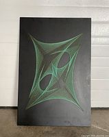 Front angled view of Mid Century String Art on black wood panel with green string in abstract geometric pattern