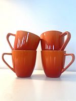 Four Le Creuset Flame 12 oz mugs stacked in pairs showing full front view and handles.