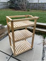 Front view of the 3-tier wooden utility cart showing all three shelves and casters.