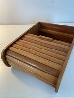 Top angled view of the teak tambour storage box showing open tambour door slats and interior storage compartment.