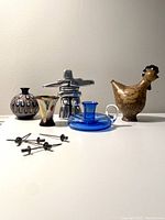 Photo showing all items in the lot including sculpture, vases, cocktail picks, candle holder, and flask
