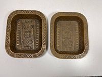 Pair of rectangular brass trays with intricate geometric etchings and decorative borders photographed from above showing pattern details and relative size.