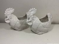 Pair of white ceramic chicken-shaped planters displayed side by side showing full profiles.