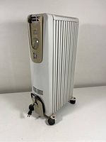 Side and front view of the white DeLonghi Dragon oil heater model HM25 with broken handle and power cord wrapped at the base.