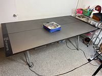 Full view of the assembled folding ping pong table top on legs with case of balls, paddles, and net on top.