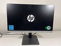 Front view of the HP monitor showing screen with HP logo and certification labels.