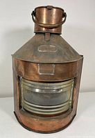 Front view of large copper ship's lantern with visible glass lens and 'PORT' label on top.