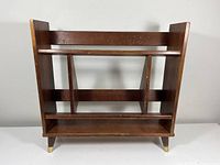 Front view of mid century wooden bookcase showing three shelves and angled sides