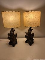 Pair of lit lamps with driftwood form bases and marbled fiberglass shades.